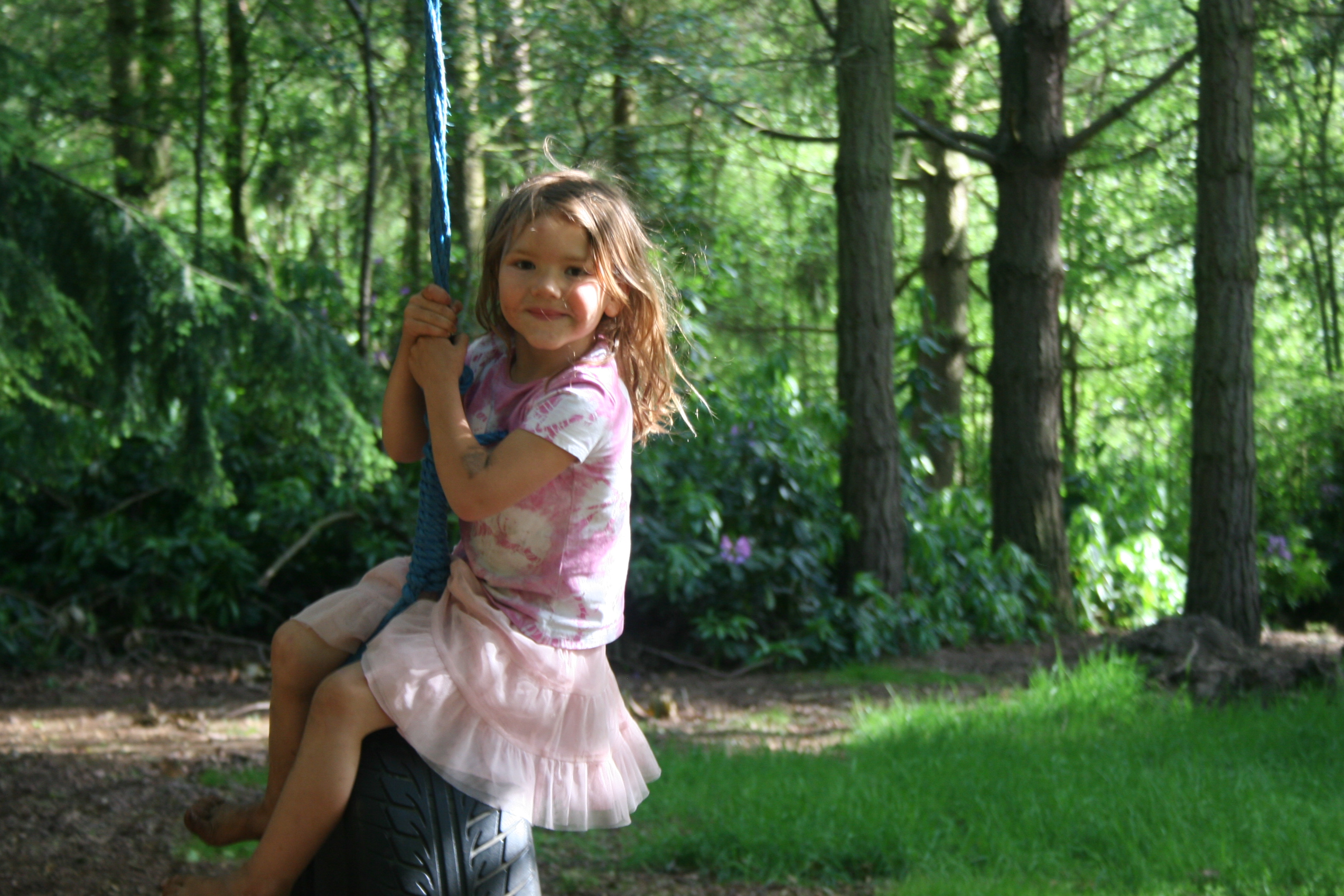 A child on a tyre swing in woodland