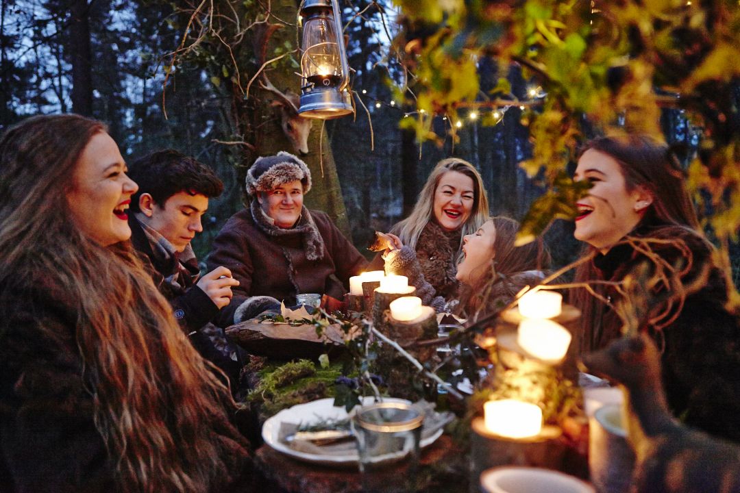 A group of people sitting at an outside table decorated with candles